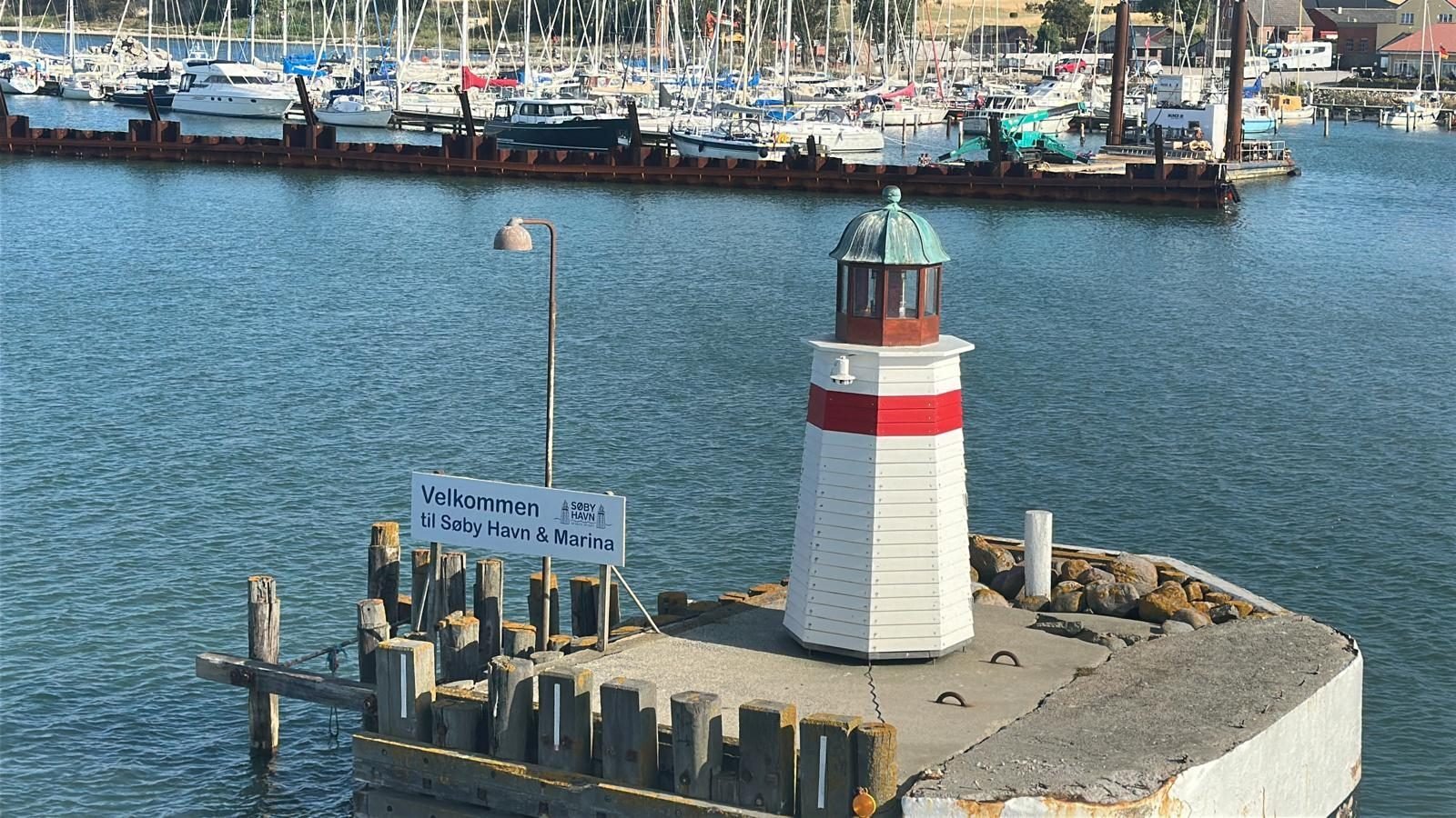 Kleiner Leuchtturm an der Hafeneinfahrt von S&oslash;by mit Willkommensschild