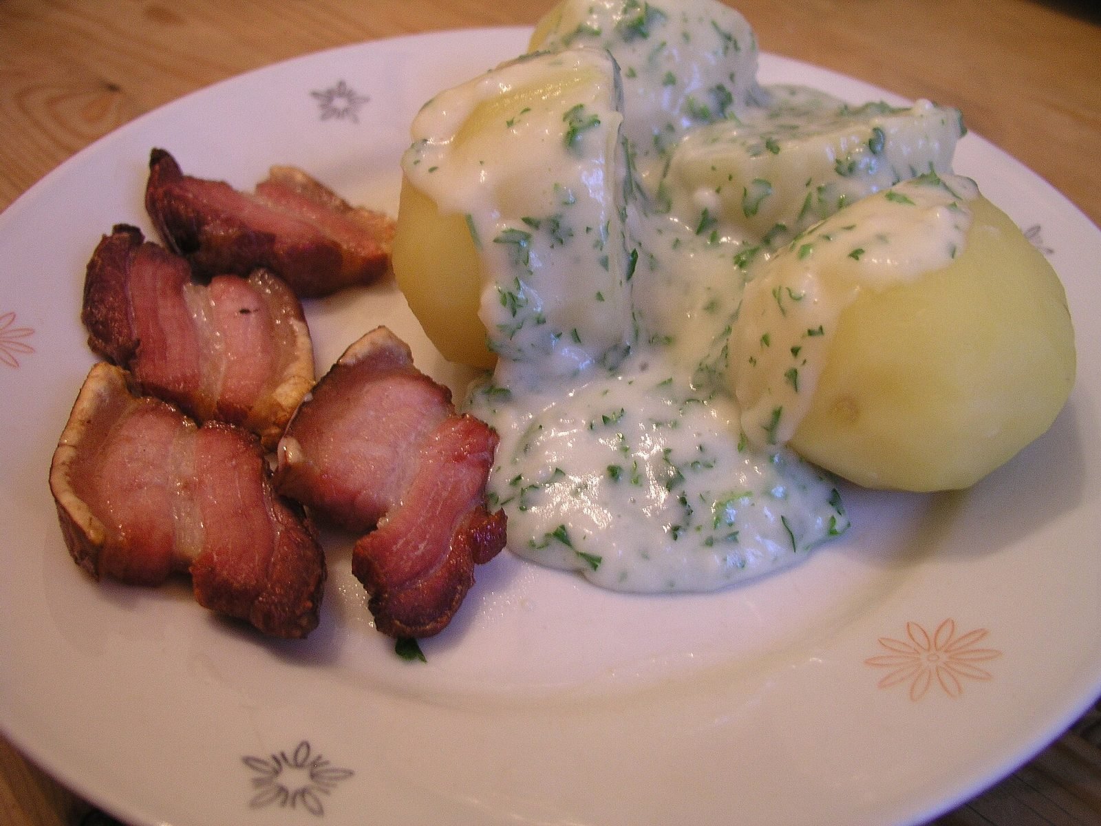 Gebratene Scheiben Schweinebauch mit Kartoffeln und Petersiliensauce auf einem wei&szlig;en Teller